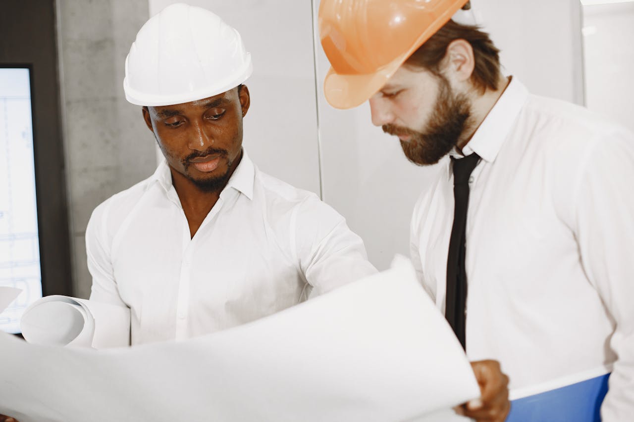 The Art of Drawing Readers In: Your attractive post title goes here Two engineers in hard hats concentrate on reviewing detailed construction blueprints indoors.